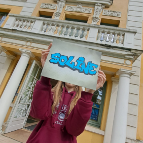 jeune fille posant avec une feuille devant son visage, sur laquelle il est écrit "Soline" en style graffiti